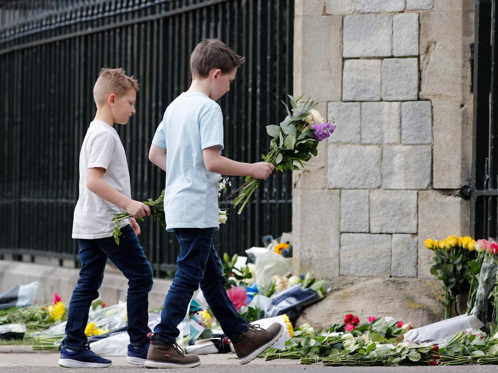 Boys add flowers to the tributes at the Cambridge Gate at Windsor Castle, in Windsor. Picture: Adrian Dennis / AFP