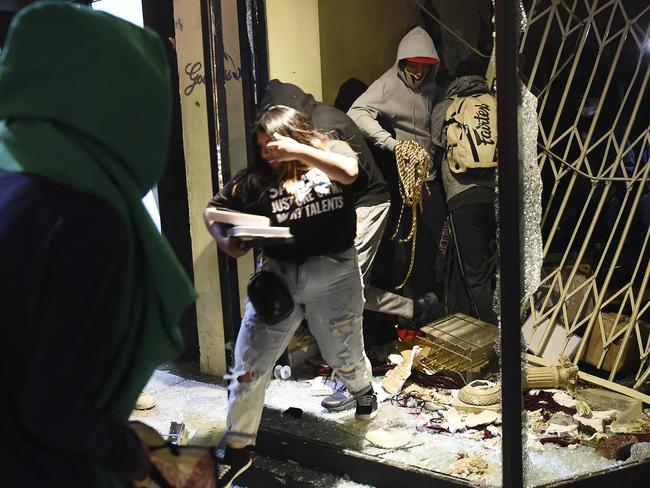 People take jewellery from the Realm of the Goddess store as looting occurs across the US during protests over the death of George Floyd. Picture: AP Photo/Chris Pizzello