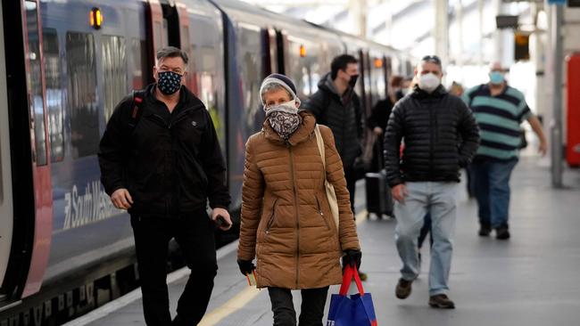 Travellers wearing protective face coverings to combat the spread of the coronavirus disembark from a train at Waterloo Station in London in late 2020. Picture: AFP