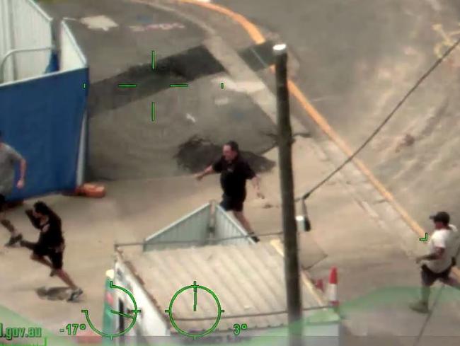 The man runs onto the construction site, chased by Reece Brown.