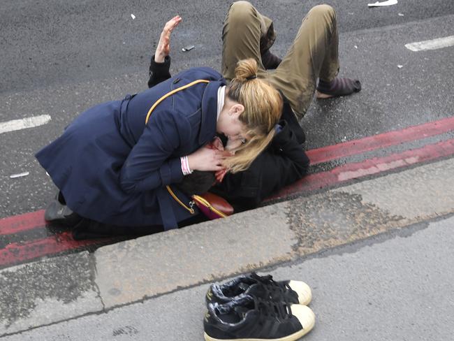 A woman assists an injured person after an incident on Westminster Bridge in London, March 22, 2017. REUTERS/Toby Melville