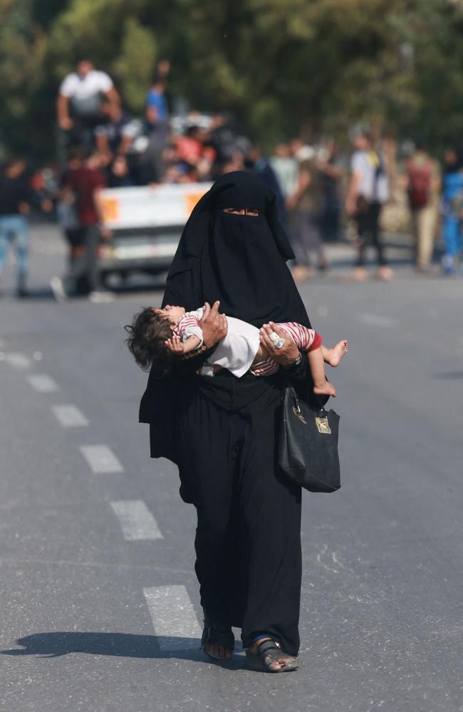 A woman carries a child as people with some of their belongings reach central Gaza Strip on foot via the Salah al-Din road on their way to the southern part of the Palestinian enclave. Picture: AFP