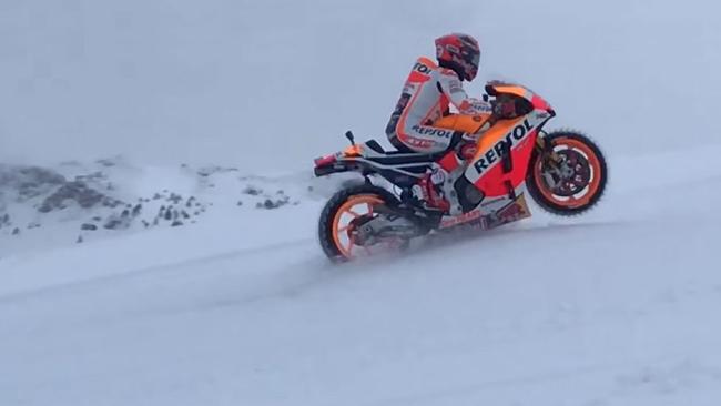 Marc Marquez riding his MotoGP bike up a ski slope.