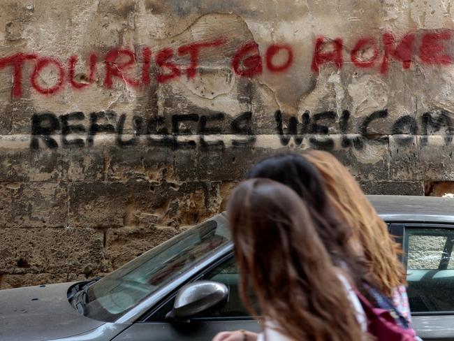 People walk past graffiti in Palma, on the Spanish island of Majorca, on May 23, 2016. Picture: Reuters/Enrique Calvo