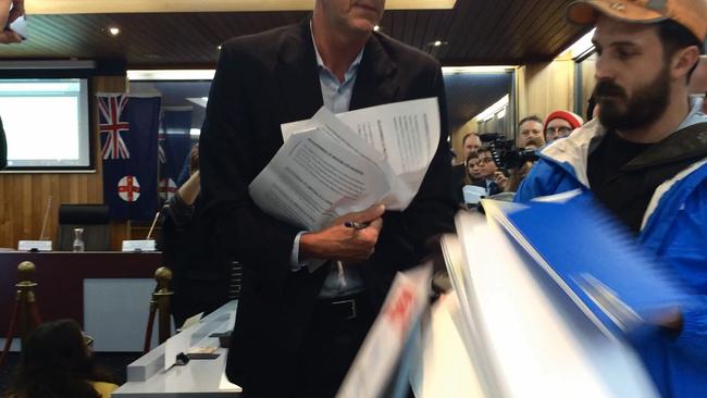 A protester knocks aside Mr Pearson, spilling his pile of council documents. Picture: Bryant Hevesi