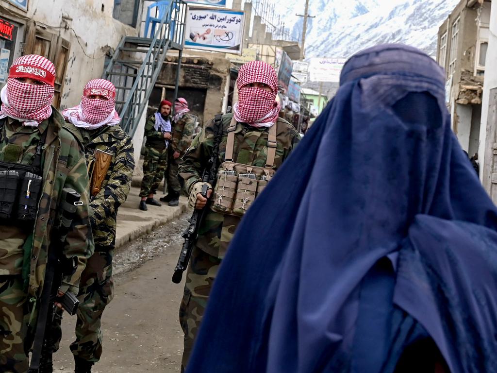 Taliban security personnel stand guard as an Afghan burqa-clad woman walks along a street at a market in the Baharak district of Badakhshan province on February 26, 2024. Picture: Wakil Kohsar/AFP