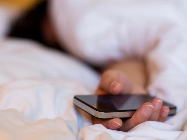 hand holding smartphone when sleeping on bed. Picture: iSTockEscape, sleeping travel wisdom, Natalia Cooper