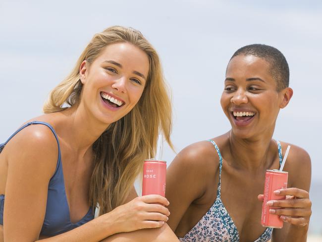 Georgie Mitchell and Lucy Blay with cans of Rose on the beach.  Picture: Dylan Robinson