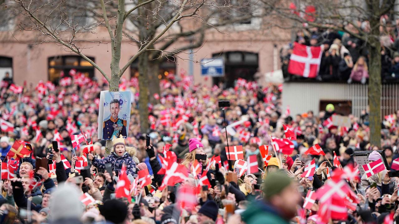 People wave flags of Demark as they wait for the crown couple to ride from the Amalienborg Castle to the Christiansborg Castle. Picture: AFP