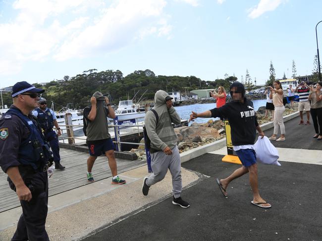 Three men disembarking from the police boat.