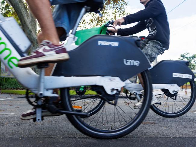 People using lime bikes without helmets, in Surry Hills, on Wednesday. Picture: Justin Lloyd