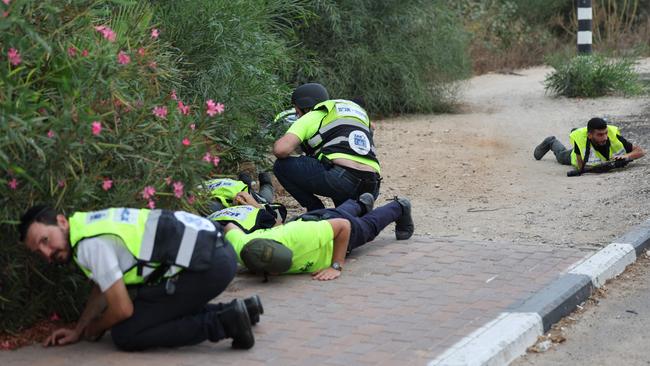 Armed Israeli emergency responders take cover during a rocket attack near the border with Gaza. Picture: Jack Guez/AFP