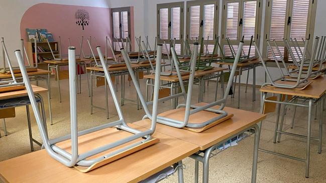 Empty classroom with upside down chairs on desks