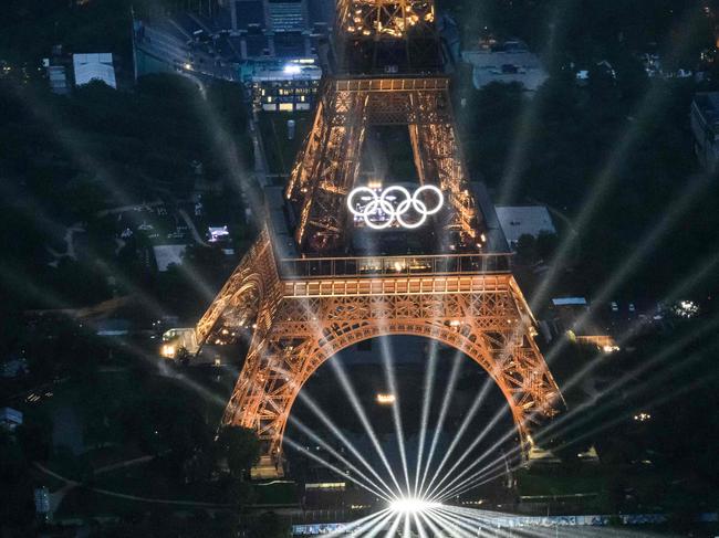 TOPSHOT - A photograph taken from an helicopter on July 26, 2024 shows an aerial view of the Eiffel Tower and the Olympics Rings lightened up during the opening ceremony of the Paris 2024 Olympic Games in Paris. (Photo by Lionel BONAVENTURE / POOL / AFP)