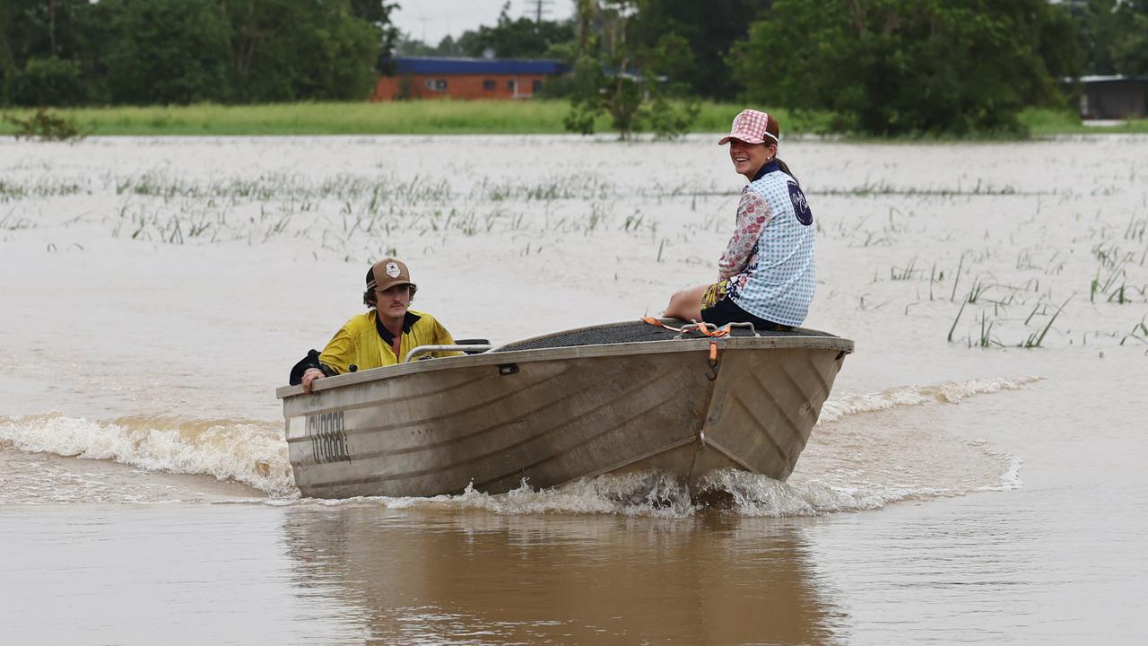 Tully residents Luke Leoni and Zarllea Balke use a tinnie to motor around flooded cane paddocks to the Euramo pub after the Bruce Highway was cut off by flood water south of the Tully River. Picture: Brendan Radke