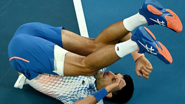 Serbia's Novak Djokovic falls as he hits a return against Bulgaria's Grigor Dimitrov.