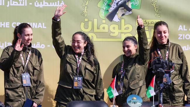 The four Israeli hostages wave on a stage before Hamas fighters hand them over to a team from the Red Cross in Gaza City on Saturday. Left to right, they are Naama Levy, Liri Albag, Daniella Gilboa and Karina Ariev. Picture: Omar Al-Qattaa / AFP