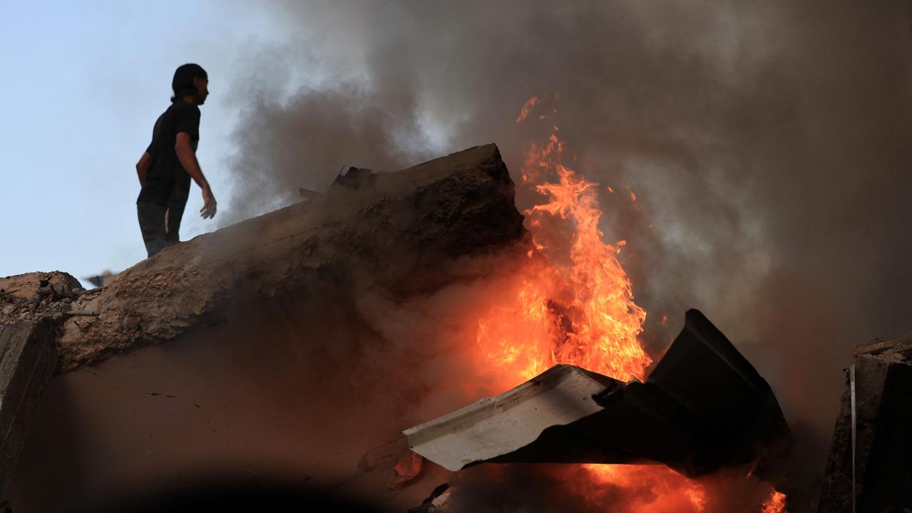 A Palestinian man stands on a concrete slab of a collapse building as a fire burns following the Israeli bombardment of Khan Yunis. Picture: AFP