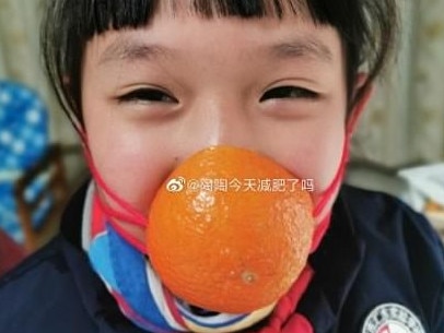 A child grins from behind her orange rind number. Picture: Weibo