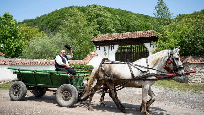 A man and his horse-drawn cart pass the gate to the property of King Charles in the Romanian village of Valea Zalanului. Picture: AFP