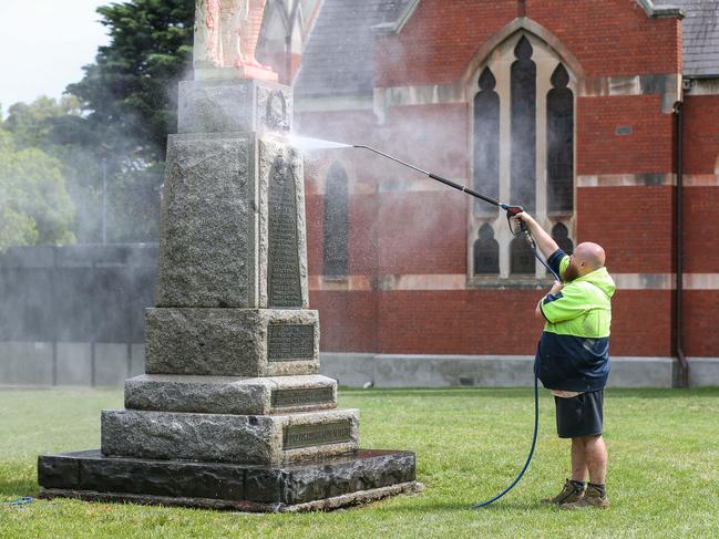 Cleaners wash paint from the Anzac statue on Saturday morning. Picture: Brendan Beckett