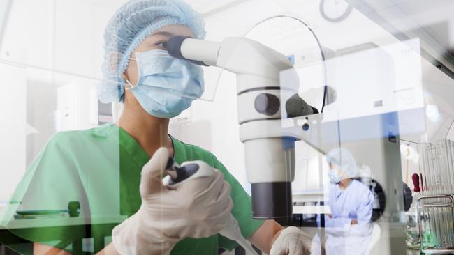 Asian scientist using microscope in the laboratory