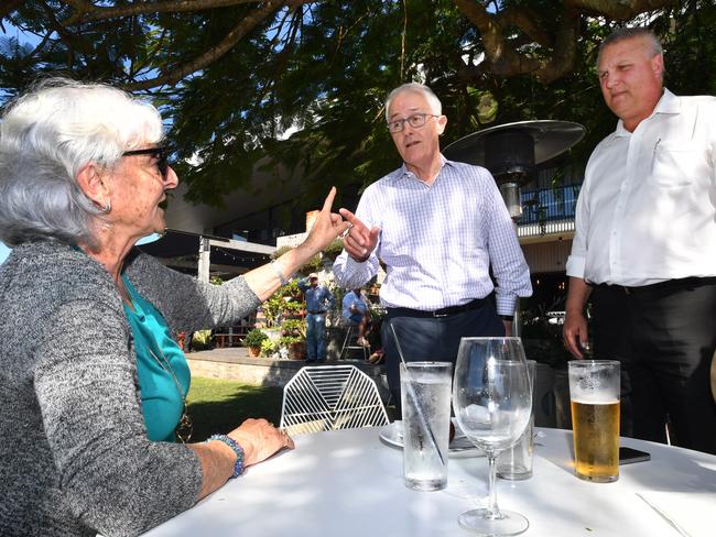 Local resident Toni Lea (left) gestures towards Prime Minister Malcolm Turnbull (centre) and LNP candidate for Longman Trevor Ruthenberg (right) at the Sandstone Point Hotel at Sandstone Point, Queensland, Friday, July 27, 2018. (AAP Image/Darren England) NO ARCHIVING