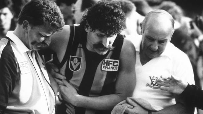 Robert DiPierdomenico is helped from the field by trainers after puncturing a lung in the 1989 Grand Final. Picture: Peter Ward.