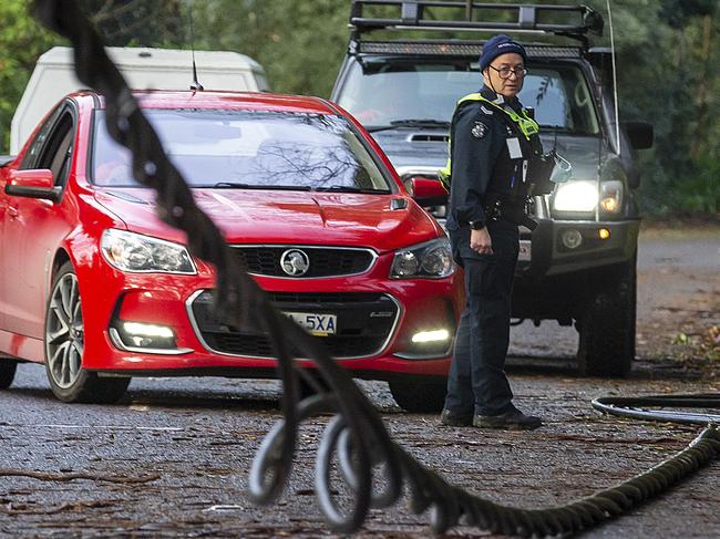 10/06/2021:  A police officer turns cars around where power lines have fallen on Monbulk Rd in Olinda after wild storms lashed the Dandenong ranges on Thursday morning. Picture: David Geraghty