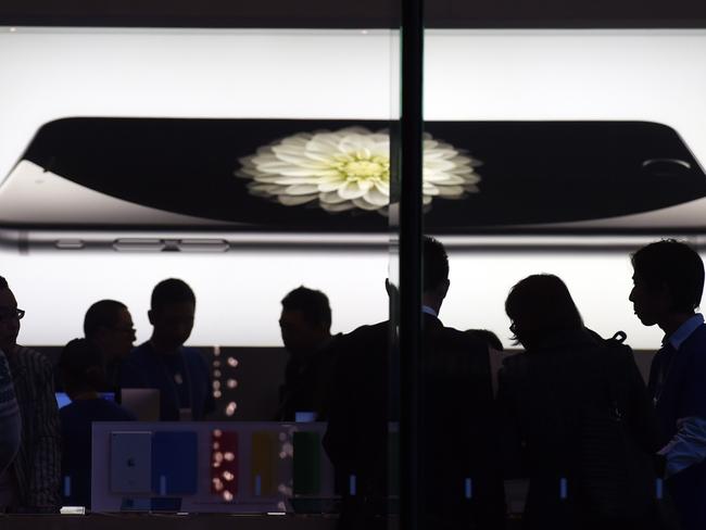 Store attendants help customers at an Apple store selling the iPhone 6 in Beijing on October 23, 2014. During a trip to Shanghai last January, Apple CEO Tim Cook said he expects China to surpass the United States to become Apple's largest market. AFP PHOTO/Greg BAKER