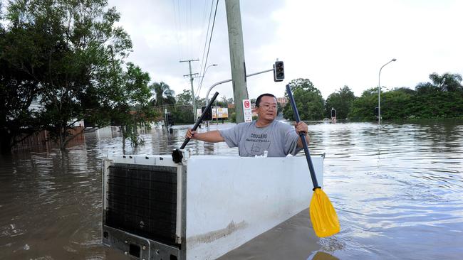 A resident paddles in a fridge in the floodwaters surrounding the central Brisbane suburb of Rosalie on Wednesday, Jan. 12, 2011.
