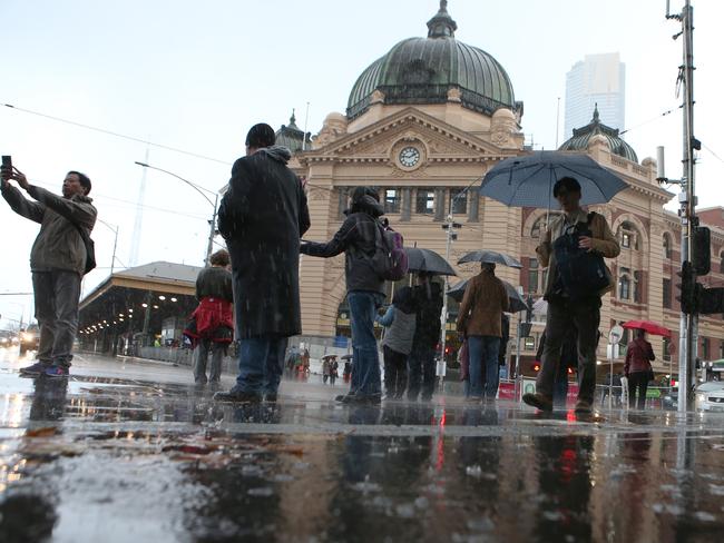 Pedestrians battle the wild weather outside Flinders Street station. AAP Image/David Crosling