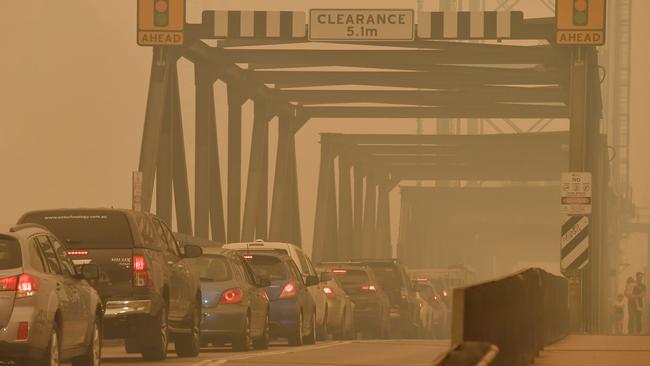 Pedestrians cross a bridge by foot as smoke haze settles over the town of Batemans Bay, New South Wales on Wednesday morning. The Princes Highway on the NSW South Coast has been closed with motorists told to avoid all non essential travel. Picture: Sam Mooy/The Australian