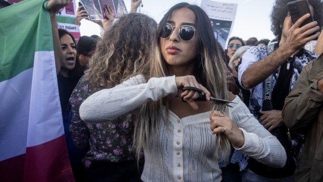 A woman cuts her hair during a protest against the death of Iranian Mahsa Amini and the government of Iran on October 2 in Istanbul, Turkey. Picture: Chris McGrath/Getty Images