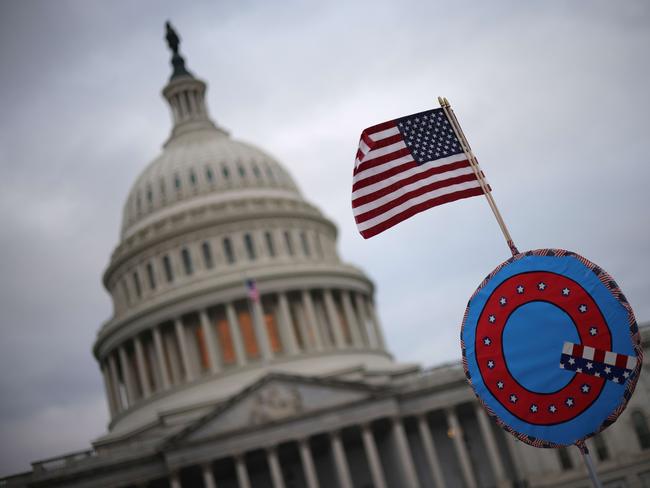 Supporters of President Donald Trump fly a US flag with a symbol from the group QAnon outside the US Capitol building. Picture: Getty Images