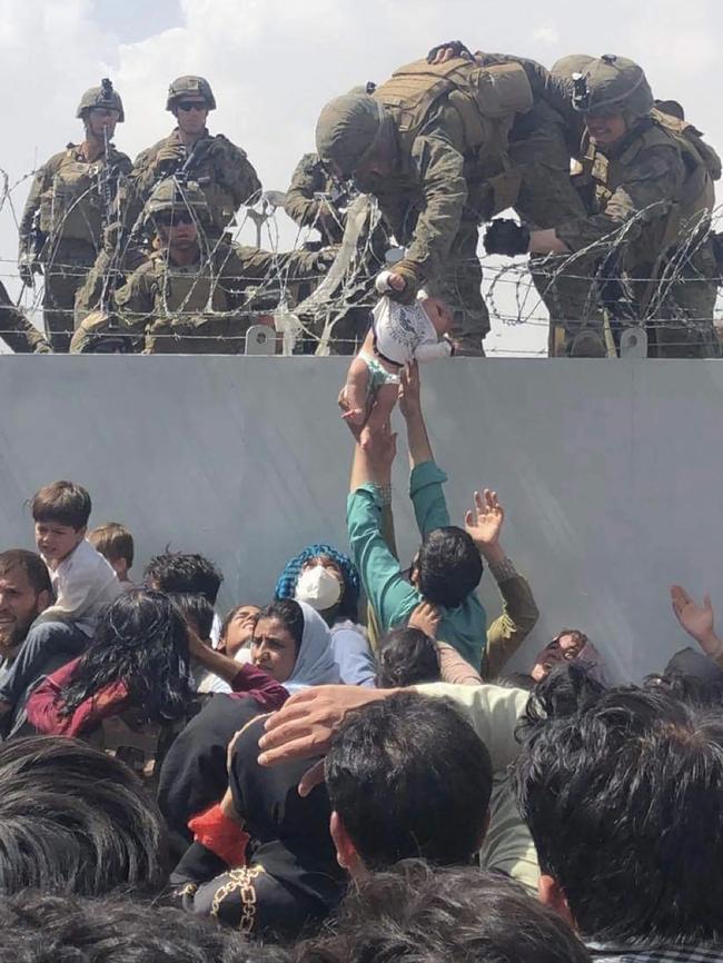 US Marine grabs an infant over a fence of barbed wire during an evacuation at Hamid Karzai International Airport in Kabul. Picture: AFP