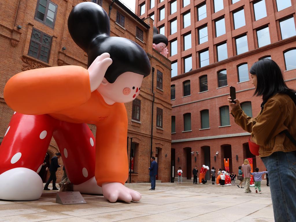 A woman takes photos of the “Tireless Girl” art installation at the Rockbund in Shanghai, China. Picture: VCG/Getty Images