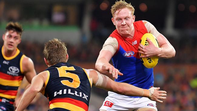 Clayton Oliver of the Demons evades a tackle from Matt Crouch of the Crows.