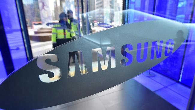 South Korean policemen pass the logo of Samsung Electronics at its showroom in Seoul on January 29, 2015. Samsung Electronics, the world's largest smartphone maker, posted its first drop in annual net profits for three years days after arch-rival Apple reported the biggest corporate profit in history. AFP PHOTO / JUNG YEON-JE