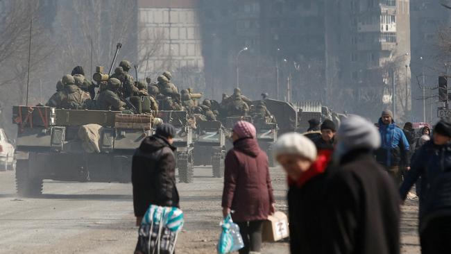 Service members of pro-Russian troops drive armoured vehicles past local residents in the besieged southern port city of Mariupol. Picture: Reuters/Alexander Ermochenko
