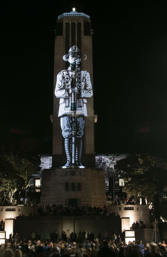 Unforgettable ... People gather to see a picture of a soldier being projected onto a tower at Pukeahu National War Memorial Park in Wellington, New Zealand. Picture: Marty Melville/AFP