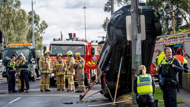 Emergency crews are attempting to remove a Ford Mustang stuck to a power pole in Kew. Picture: Jake Nowakowski