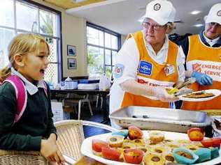 Storm victim Arancaria Velasco, 8, of Lennox Head, is served breakfast by Salvation Army volunteers June Lock (left) and Wilma Grace at the Lennox Head Bowling Club emergency centre before leaving for school. . Picture: Jay Cronan