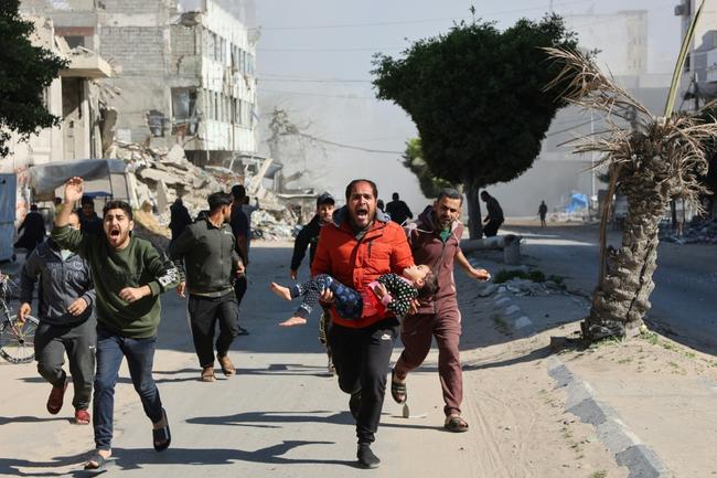 Palestinians rush an injured girl away from the site of Israeli strikes on a makeshift displacement camp in Gaza City