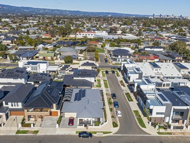 Aerial view looking down on new, modern Adelaide housing development with mixed house & architectural styles: single level houses, townhouses, construction site, green space, established suburb & city in background. Picture: iStock/BeyondImages