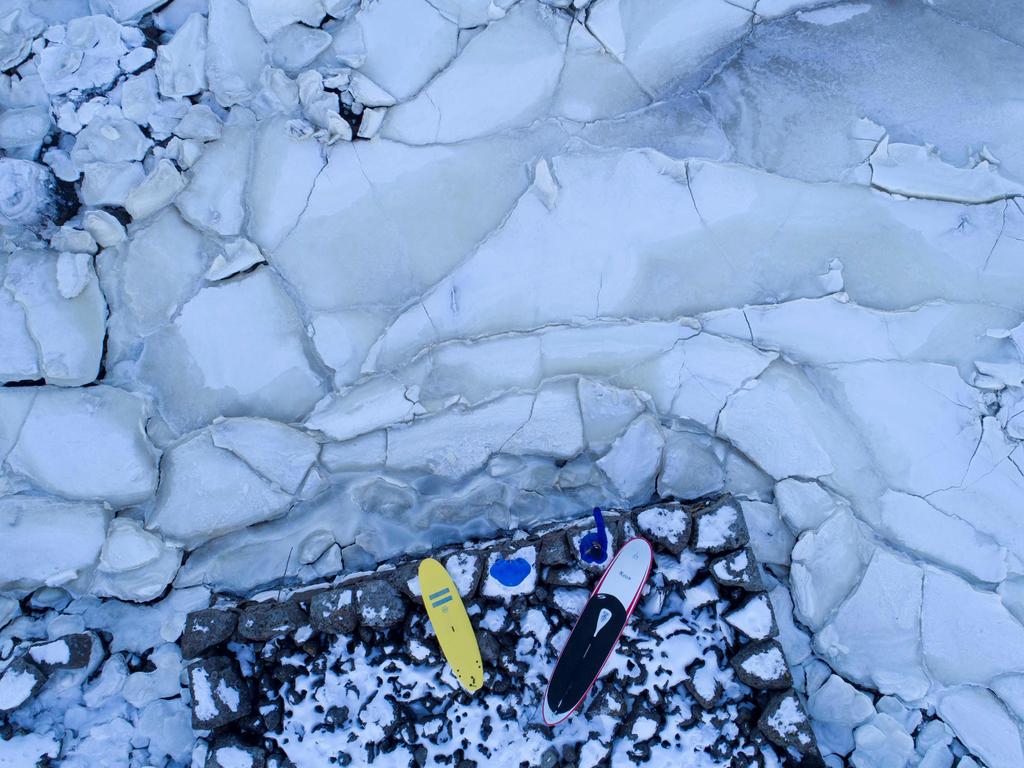 Surfers look at the water from ice plates, on March 5, 2018 in Henningsvaer, northern Norway, Lofoten islands, within the Arctic Circle as air temperature drops minus 13°C and water temperature above 4°C.Picture: AFP