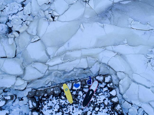 Surfers look at the water from ice plates, on March 5, 2018 in Henningsvaer, northern Norway, Lofoten islands, within the Arctic Circle as air temperature drops minus 13°C and water temperature above 4°C.Picture: AFP