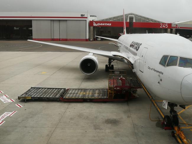 Australia's national carrier Qantas today announced a half year loss of $252 million and they will cut 5000 full time staff over the next 3 years. A Boeing 767 sits at a gate ready for boarding at Sydney airport.