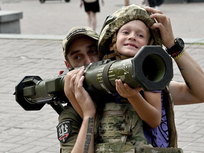 Commissars, accused of “treason”, were responsible for conscripting fighting aged men and women. A Ukrainian serviceman helps a boy hold an antitank weapon. Picture: AFP