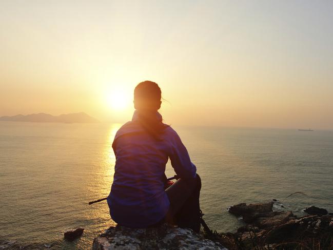 woman hiker sit on rock face the sunrise